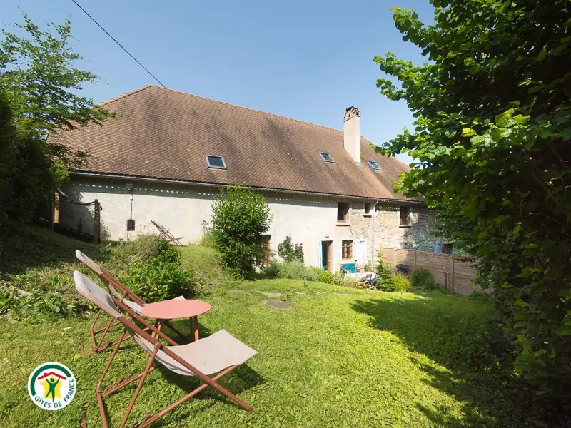 La bâtisse en pierre et le jardin en pente du gîte, en été