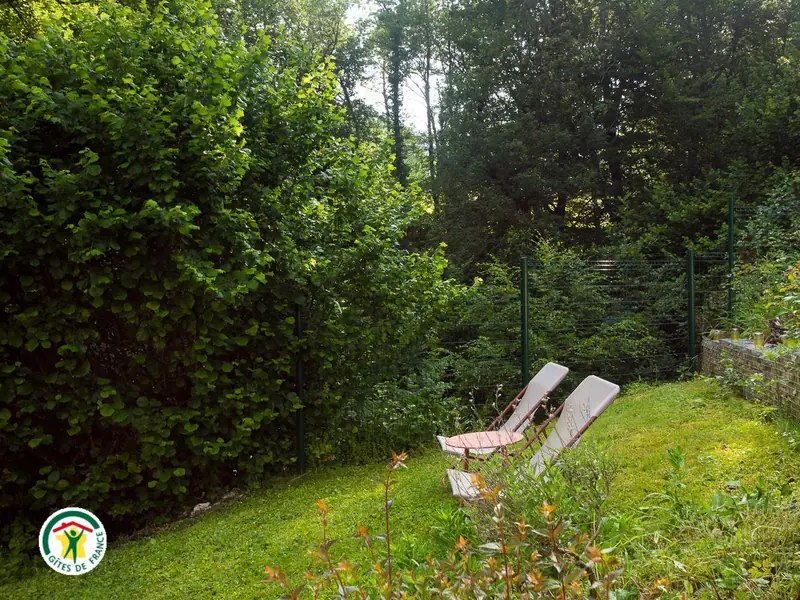 Deux transats à l'ombre des arbres, dans le jardin clos du gîte